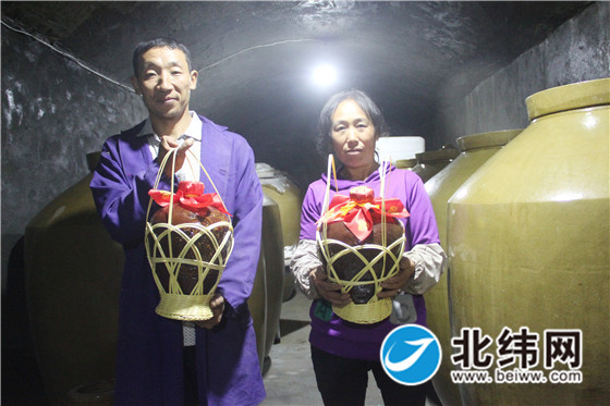 王友国（左）和妻子展示酿好的酒.jpg